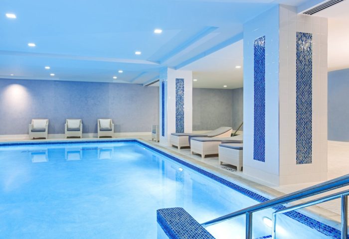 Indoor pool at the gay-friendly JW Marriott Chicago hotel. Relaxing space with lounge chairs, blue accents, and bright lighting.