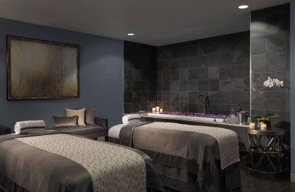 JW Marriott Chicago gay-friendly hotel's spa. Two massage tables face a tub with rose petals and candles. Relaxing gay travel experience.