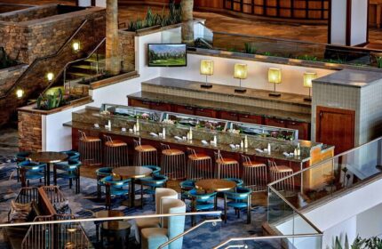Interior of JW Marriott Desert Springs Resort & Spa, a gay-friendly hotel. Bar area with seating, tables, and stairs in a stylish setting.