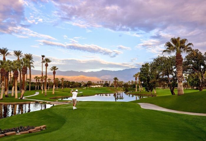 JW Marriott Desert Springs Resort & Spa golf course. Man teeing off. Palm trees, mountains, water features. Gay-friendly hotel.