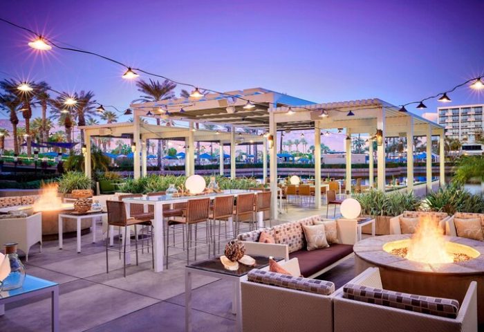 JW Marriott Desert Springs Resort & Spa outdoor patio at dusk. Gay-friendly hotel with fire pits, seating, and lights. Palm Springs getaway.