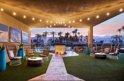 JW Marriott Desert Springs Resort & Spa patio. Stylish seating, palm trees, & mountain views. Gay-friendly hotel for relaxing travel.