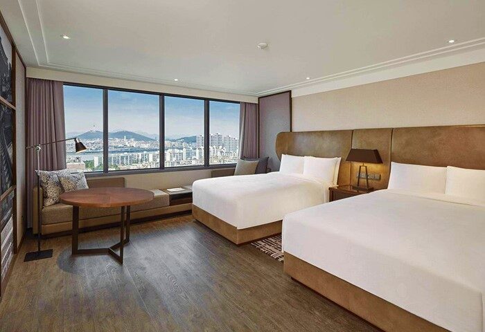 JW Marriott Hotel Seoul: Gay-friendly hotel room with 2 beds, city view, table, & seating area. Great for gay travelers' Seoul visit.