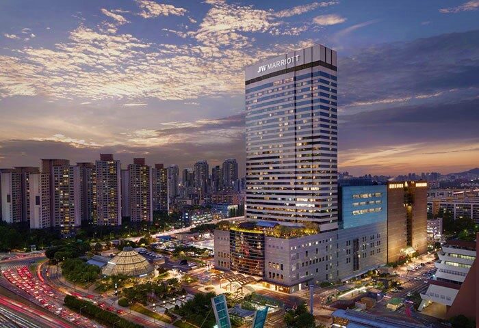 JW Marriott Hotel Seoul exterior view at dusk. Gay-friendly hotel with modern architecture. Cityscape with traffic and cloudy sky.