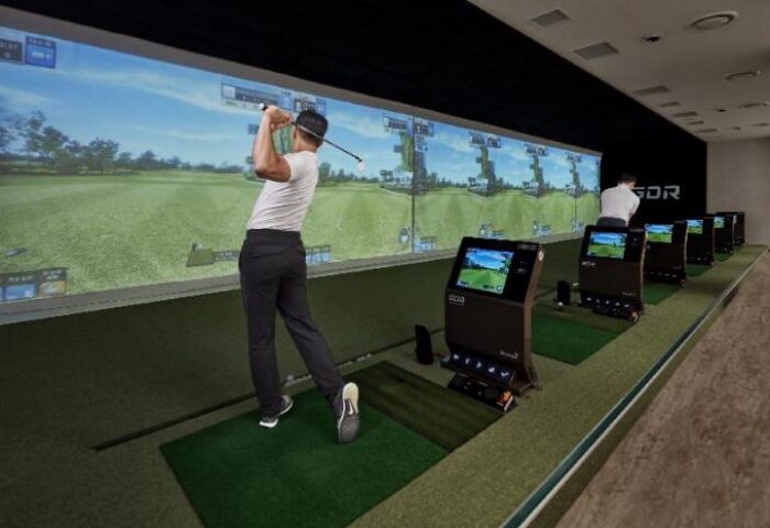 JW Marriott Hotel Seoul: Gay-friendly hotel golf simulator. Man swings golf club at screen. Indoor golf at this Seoul hotel is a fun activity.