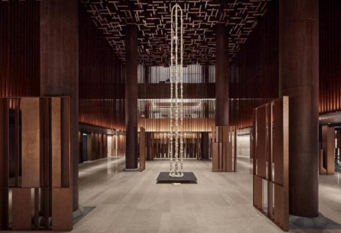 JW Marriott Hotel Seoul lobby interior. Modern design with tall columns, wood accents, and a striking central light fixture. Gay-friendly hotel.