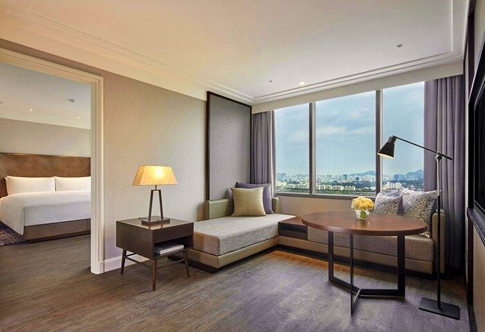 JW Marriott Hotel Seoul room interior. Gay-friendly hotel with city view, bed, couch, table, and lamp. Luxury accommodations in Seoul.