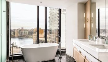 JW Marriott Parq Vancouver gay-friendly hotel bathroom. Bathtub with city view. Upscale design, marble floor, and modern fixtures.