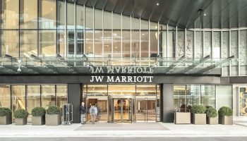 JW Marriott Parq Vancouver entrance. Gay-friendly hotel with revolving doors, modern design, and staff welcoming guests. Luxury travel.