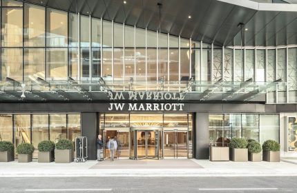JW Marriott Parq Vancouver entrance. Gay-friendly hotel with revolving doors, modern design, and staff welcoming guests. Luxury travel.