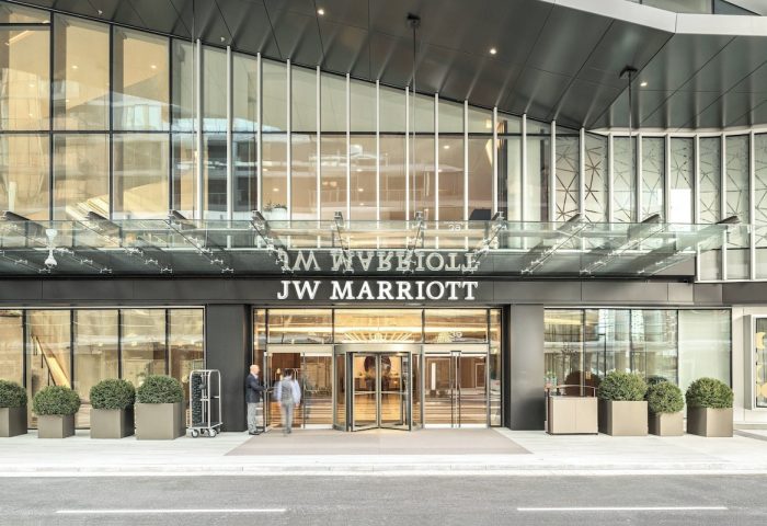 JW Marriott Parq Vancouver entrance. Gay-friendly hotel with revolving doors, modern design, and staff welcoming guests. Luxury travel.