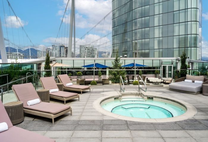 JW Marriott Parq Vancouver's outdoor pool area. This gay-friendly hotel features lounge chairs, a hot tub, and city views.