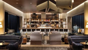 JW Marriott Parq Vancouver gay-friendly hotel bar area. Modern design with bar stools, lounge seating, and a fully stocked bar. Upscale ambiance.