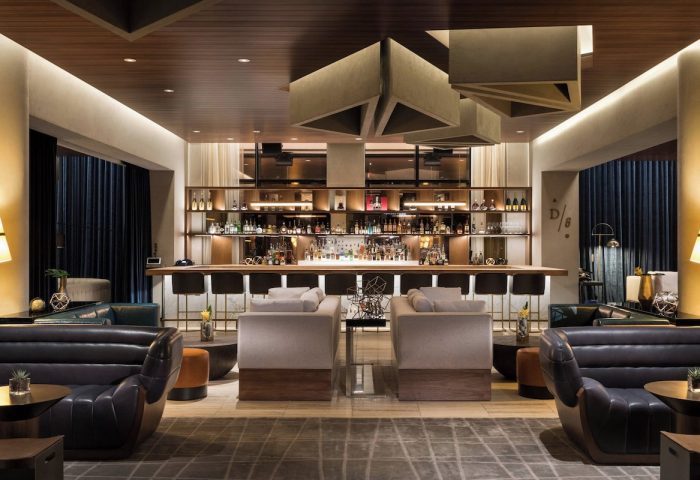 JW Marriott Parq Vancouver gay-friendly hotel bar area. Modern design with bar stools, lounge seating, and a fully stocked bar. Upscale ambiance.