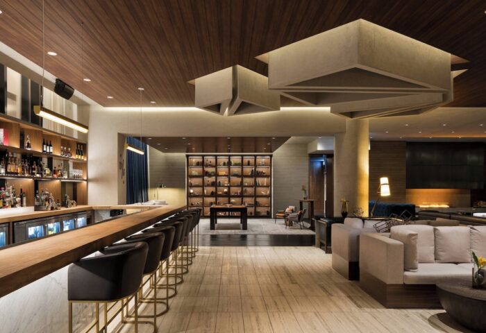 Interior of gay-friendly JW Marriott Parq Vancouver hotel. Bar with stools, lounge seating, decorative ceiling, and display case. Upscale design.