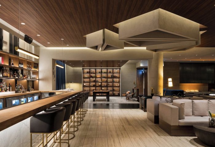 Interior of gay-friendly JW Marriott Parq Vancouver hotel. Bar with stools, lounge seating, decorative ceiling, and display case. Upscale design.