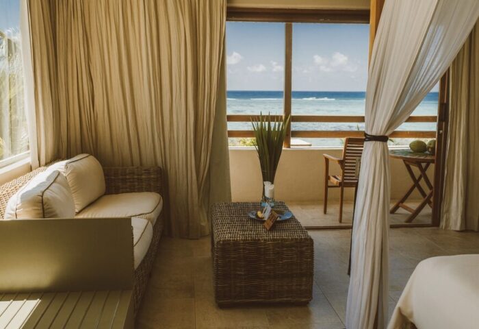 Jashita Hotel room with ocean view. Gay-friendly hotel with balcony, wicker furniture, and sheer curtains. A tranquil, luxury travel destination.