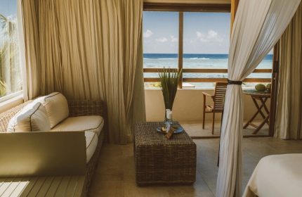 Jashita Hotel room with ocean view. Gay-friendly hotel with balcony, wicker furniture, and sheer curtains. A tranquil, luxury travel destination.