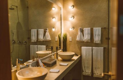 Bathroom at Gay-Friendly Jashita Hotel: Double sinks, towels with hotel logo, and modern lighting. Luxury travel for gay men in a stylish resort.