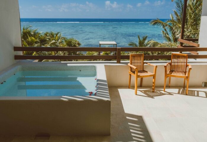 Jashita Hotel's gay-friendly rooms offer ocean views. Balcony with jacuzzi, chairs, and turquoise sea. Ideal for gay travel and relaxation.