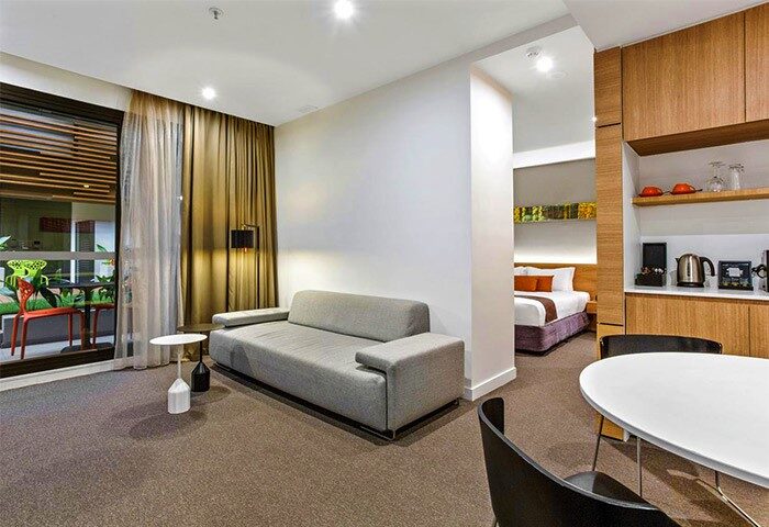Jasper Boutique Hotel's gay-friendly room. View of the living area, balcony, bed, and kitchenette. Modern design for gay men travelers.