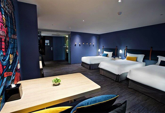 Just Sleep Hotel Ximending triple room. Gay-friendly hotel with three beds, desk, and colorful wall art. Ideal for gay travelers in Taipei.