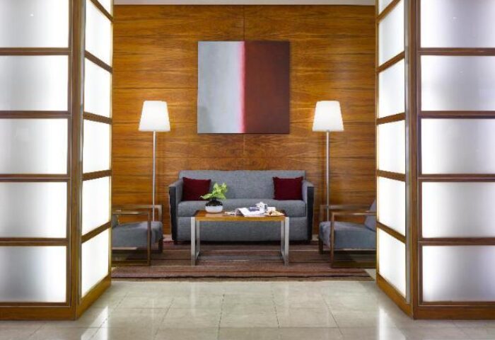 K+K Hotel Fenix lobby. Gay-friendly, pet-friendly hotel with modern decor. Seating area with sofa, chairs, and art. Welcoming space for travelers.