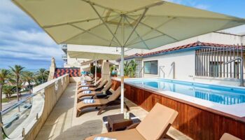 Kalma Sitges Hotel's gay-friendly rooftop pool. Lounge chairs line the deck, offering ocean views. A relaxing spot for gay travelers in Sitges.
