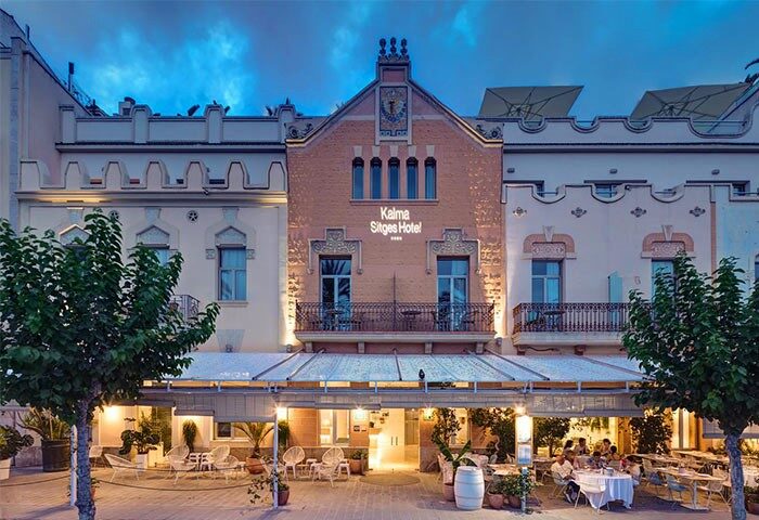 Facade of Kalma Sitges Hotel, a gay-friendly hotel in Sitges, Spain. Outdoor seating area visible. Ideal for gay travel.
