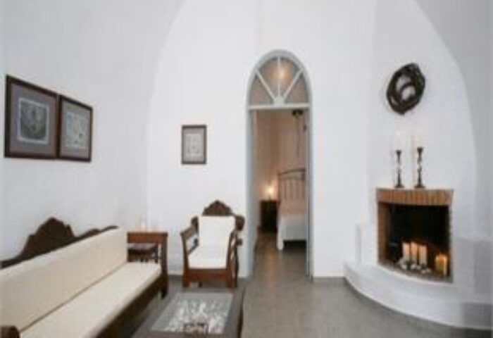 Kamares Apartments interior. Gay-friendly hotel room with white walls, fireplace, and view into the bedroom. Perfect for gay travel.