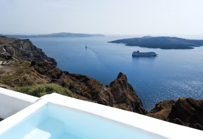 Kamares Apartments gay-friendly hotel view. Pool overlooking Santorini caldera, Aegean Sea, cruise ship, and islands. Gay travel.