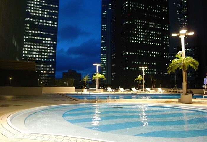 Keio Plaza Hotel Tokyo gay-friendly pool at night. High-rise buildings surround the pool area. A great choice for gay travelers.