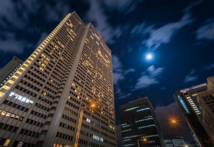 Keio Plaza Hotel Tokyo at night. Gay-friendly hotel with illuminated windows against a cloudy, moonlit sky. Tokyo, Japan skyscraper.