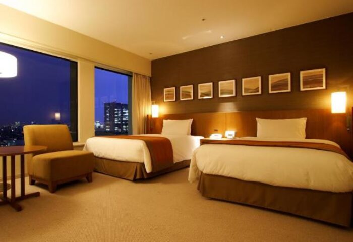 Keio Plaza Hotel Tokyo room. Gay-friendly hotel with twin beds, chair, and city view. A comfortable stay for gay travelers in Tokyo, Japan.