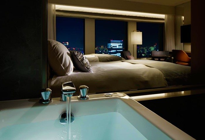 Gay-friendly Keio Plaza Hotel Tokyo room view. Bathtub with city view. Luxury hotel for gay men's travel in Tokyo, Japan. Night cityscape.