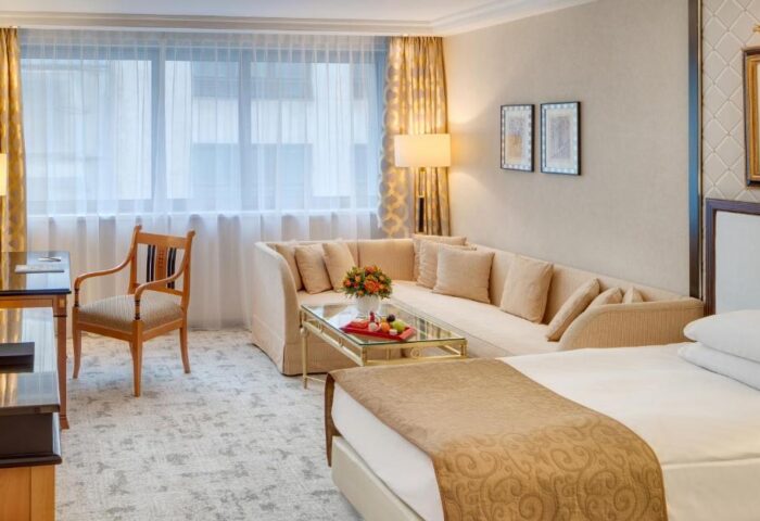 Kempinski Hotel Corvinus Budapest room. Gay-friendly, pet-friendly hotel with bed, couch, desk, chair, and window. Luxury hotel for gay men.