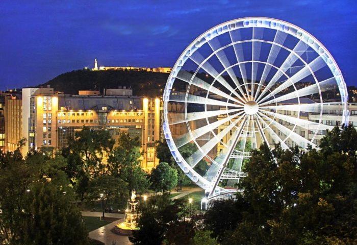 Kempinski Hotel Corvinus Budapest view at night. Ferris wheel, city lights, and a statue on a hill. Gay-friendly, pet-friendly hotel.