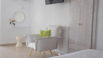Keti Hotel room: Interior view of a gay-friendly hotel. Features a chair, TV, closet, and minimalist decor. Ideal for gay men travel.