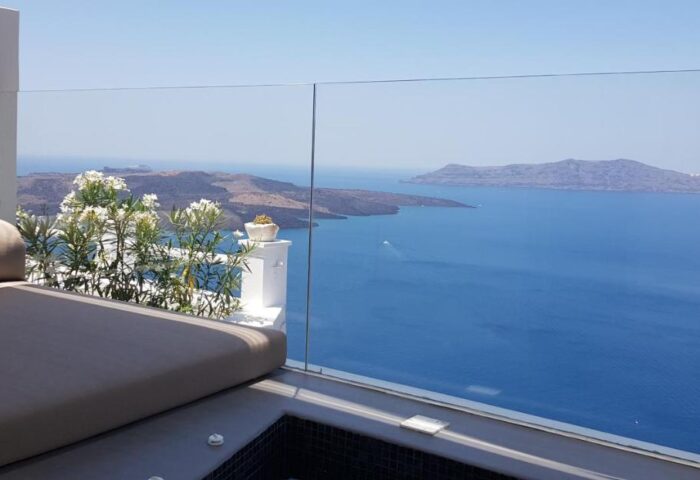 Keti Hotel, gay-friendly Santorini stay. Balcony view from a gay hotel with daybed, flowers, and ocean vista. Keti Hotel, gay travel.