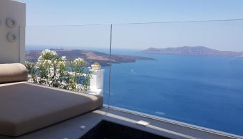 Keti Hotel, gay-friendly Santorini stay. Balcony view from a gay hotel with daybed, flowers, and ocean vista. Keti Hotel, gay travel.