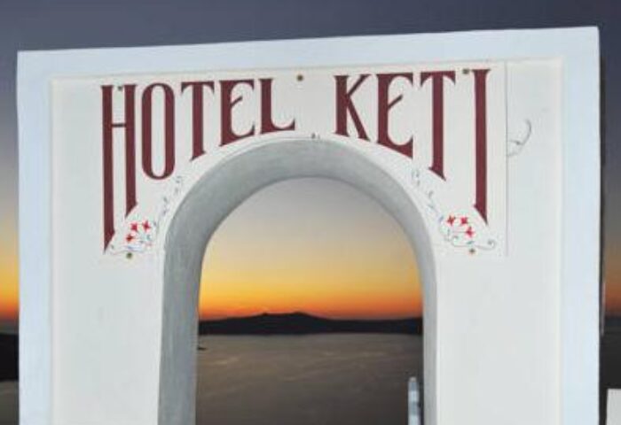 Hotel Keti sign, gay-friendly hotel. Sunset view through archway. Keti Hotel is a great option for gay men's travel in Santorini.