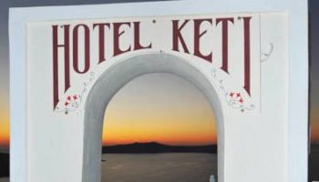 Hotel Keti sign, gay-friendly hotel. Sunset view through archway. Keti Hotel is a great option for gay men's travel in Santorini.