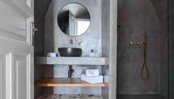 Keti Hotel's bathroom. Gay-friendly hotel featuring a modern sink, shower, round mirror, and terrazzo floor. Perfect for gay travel.