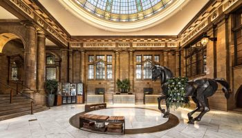 Kimpton Clocktower Hotel's lobby. Gay-friendly hotel with a horse statue, marble floor, and glass dome. Ideal for gay men's travel in Manchester.