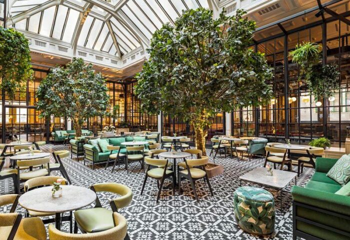 Kimpton Clocktower Hotel's gay-friendly interior. A bright atrium with trees, seating, and a patterned floor. Ideal for gay travel advice.
