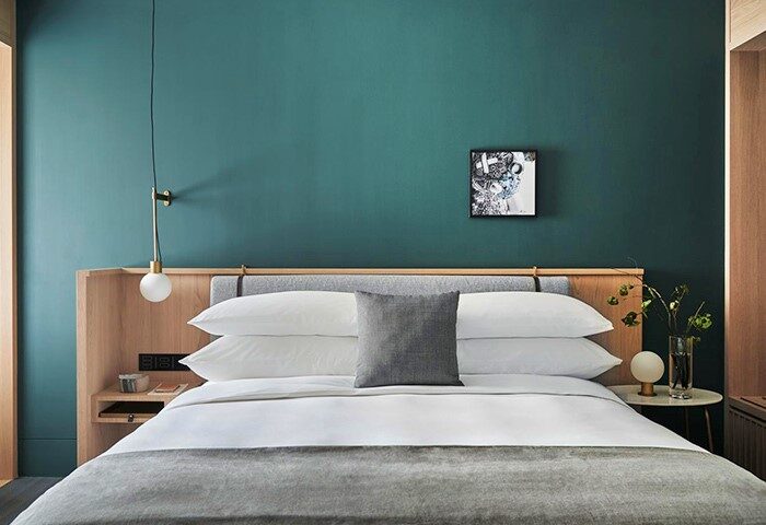 Kimpton Da An Hotel bedroom. Stylish, gay-friendly hotel room with teal wall, modern lamp, and minimalist decor. Ideal for gay travel in Taipei.