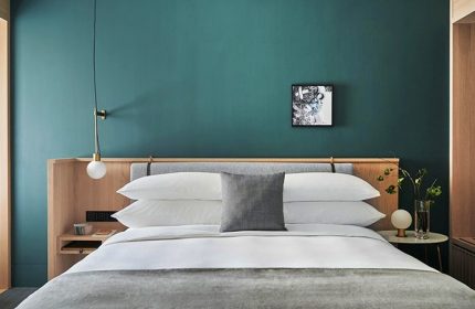 Kimpton Da An Hotel bedroom. Stylish, gay-friendly hotel room with teal wall, modern lamp, and minimalist decor. Ideal for gay travel in Taipei.