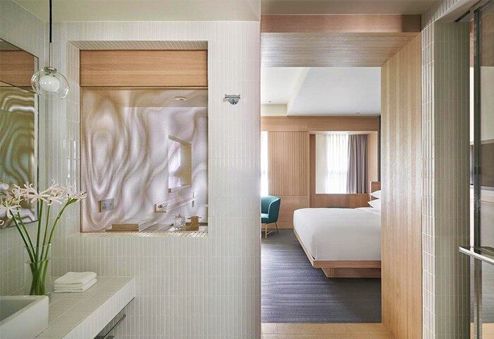 Kimpton Da An Hotel bathroom. Gay-friendly hotel room view with a bed, chair, and bathroom sink. Modern design for gay travel.