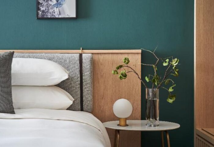 Kimpton Da An Hotel bedroom detail. Gay-friendly hotel with stylish decor, featuring a bed, bedside table, and modern lamp. Taiwan travel.