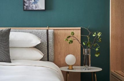 Kimpton Da An Hotel bedroom detail. Gay-friendly hotel with stylish decor, featuring a bed, bedside table, and modern lamp. Taiwan travel.